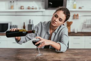 woman pouring wine considers if mom drinks too much