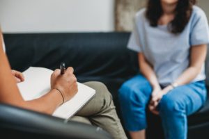 woman in grey shirt talks with a therapist about addiction replacement