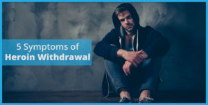 man sitting on the floor experiencing symptoms of heroin withdrawal