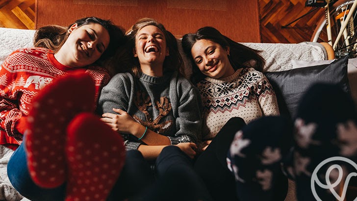 three girls laughing with feet up in the air
