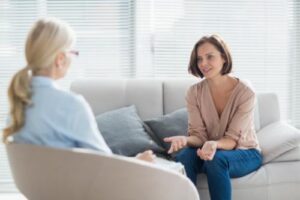 a patient sits on a couch talking to her therapist about carelon behavioral health insurance coverage for addiction treatment and if it covers her treatment