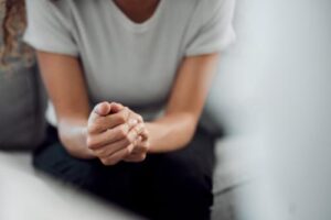 a person sits with their hands clasped together while in their ptsd treatment program